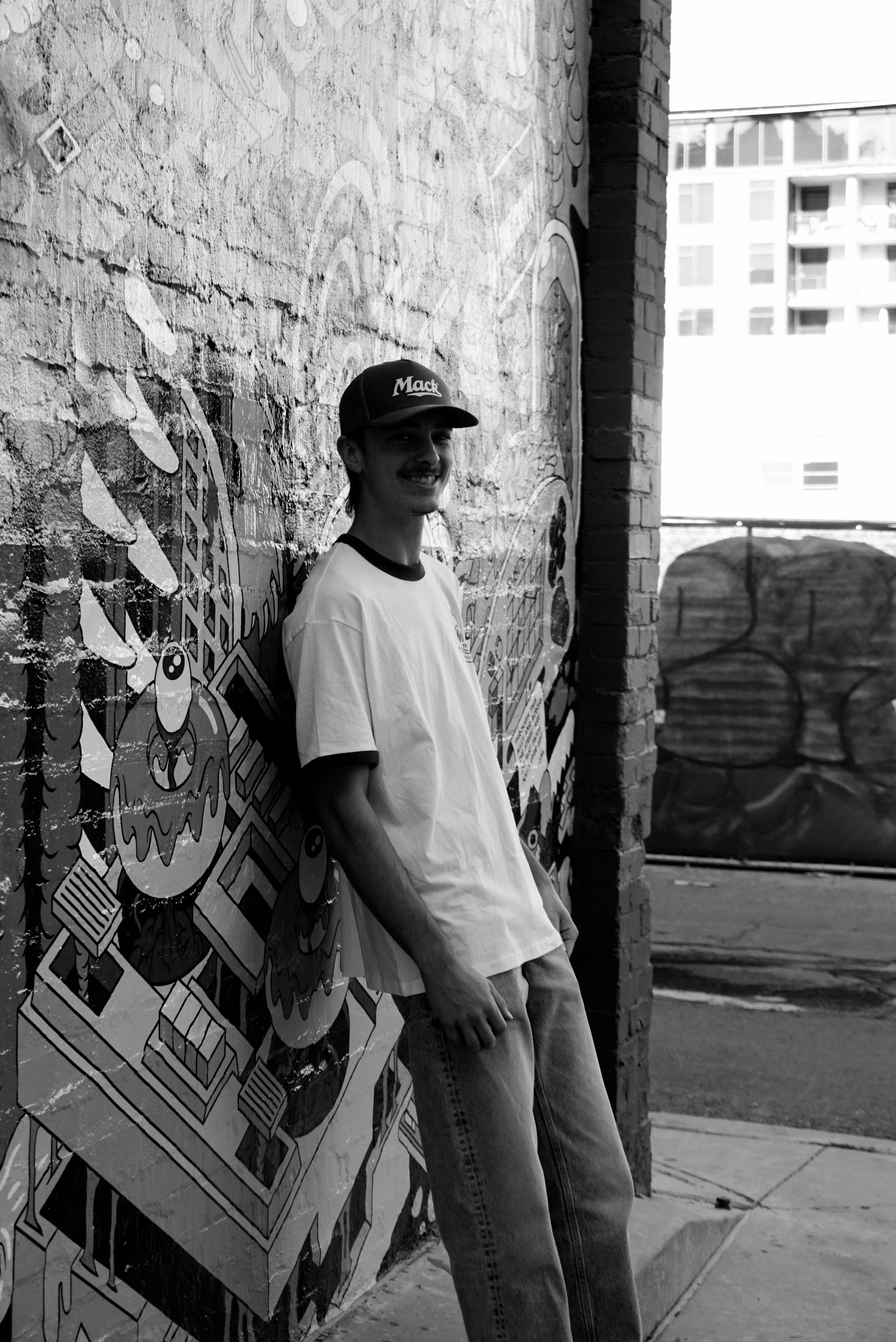 Portrait — Young man against a graffiti wall in black and white