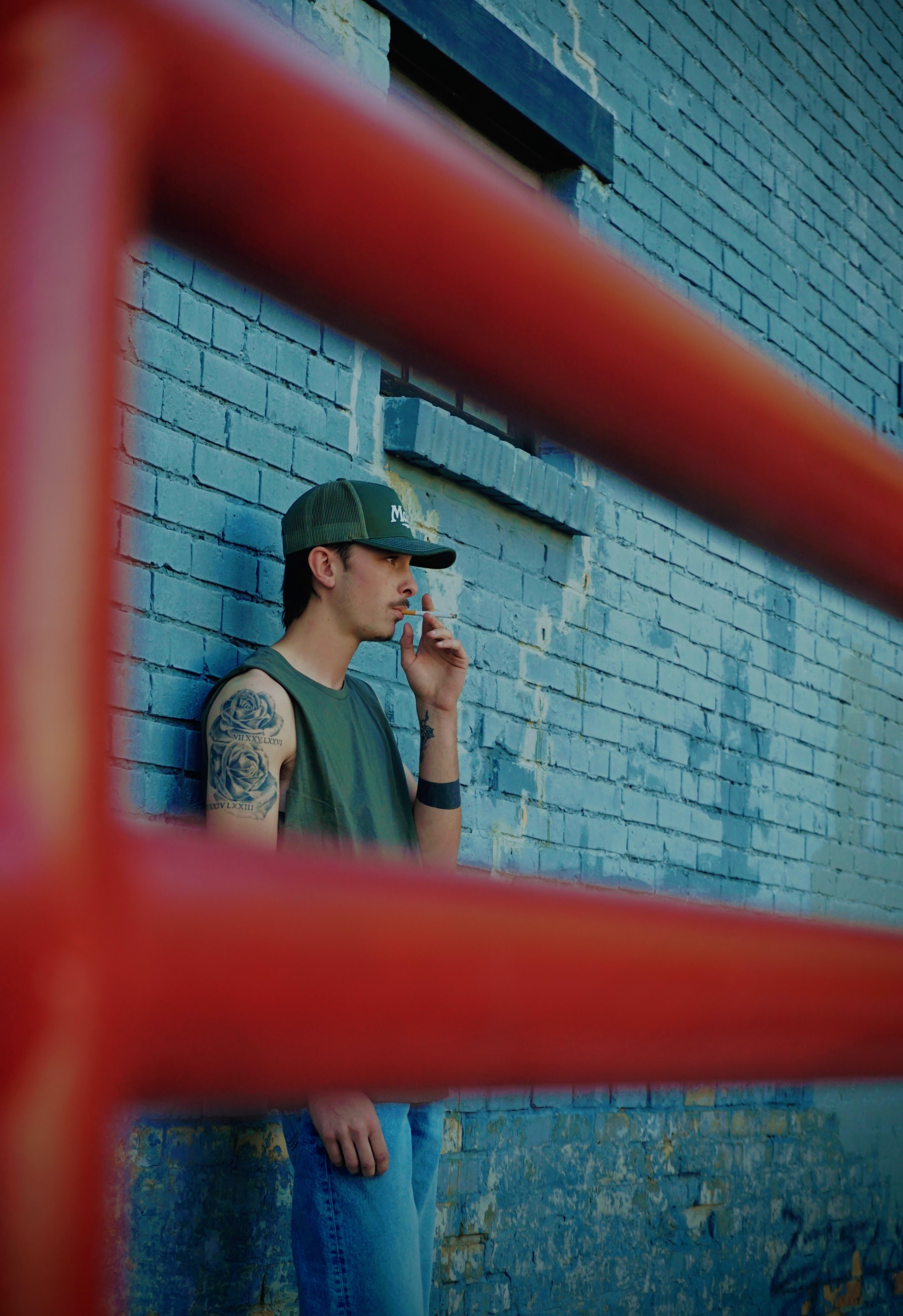 Portrait — Man seen through red industrial rails