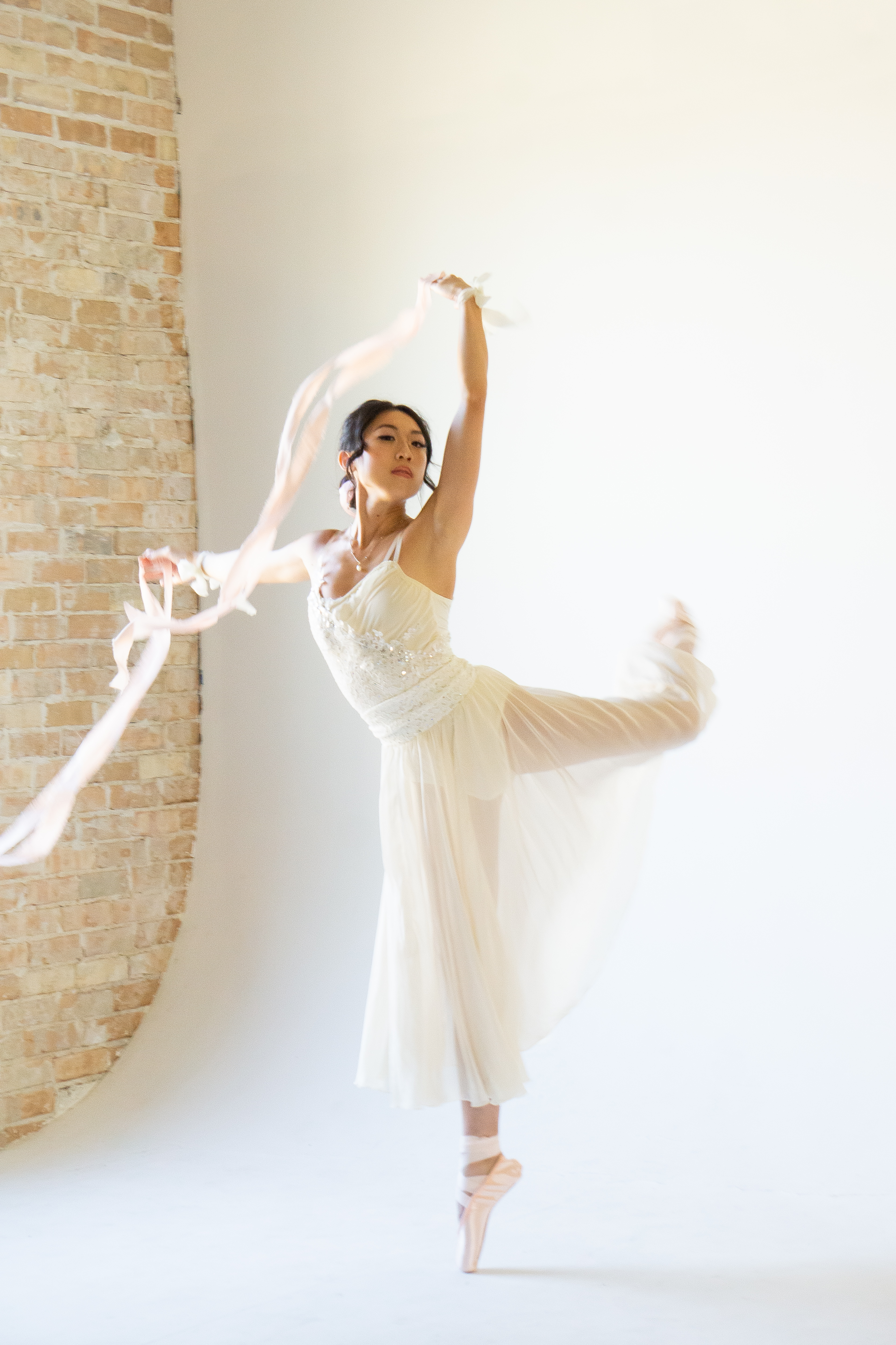 Fashion — Ballerina with flowing ribbons in a bright studio