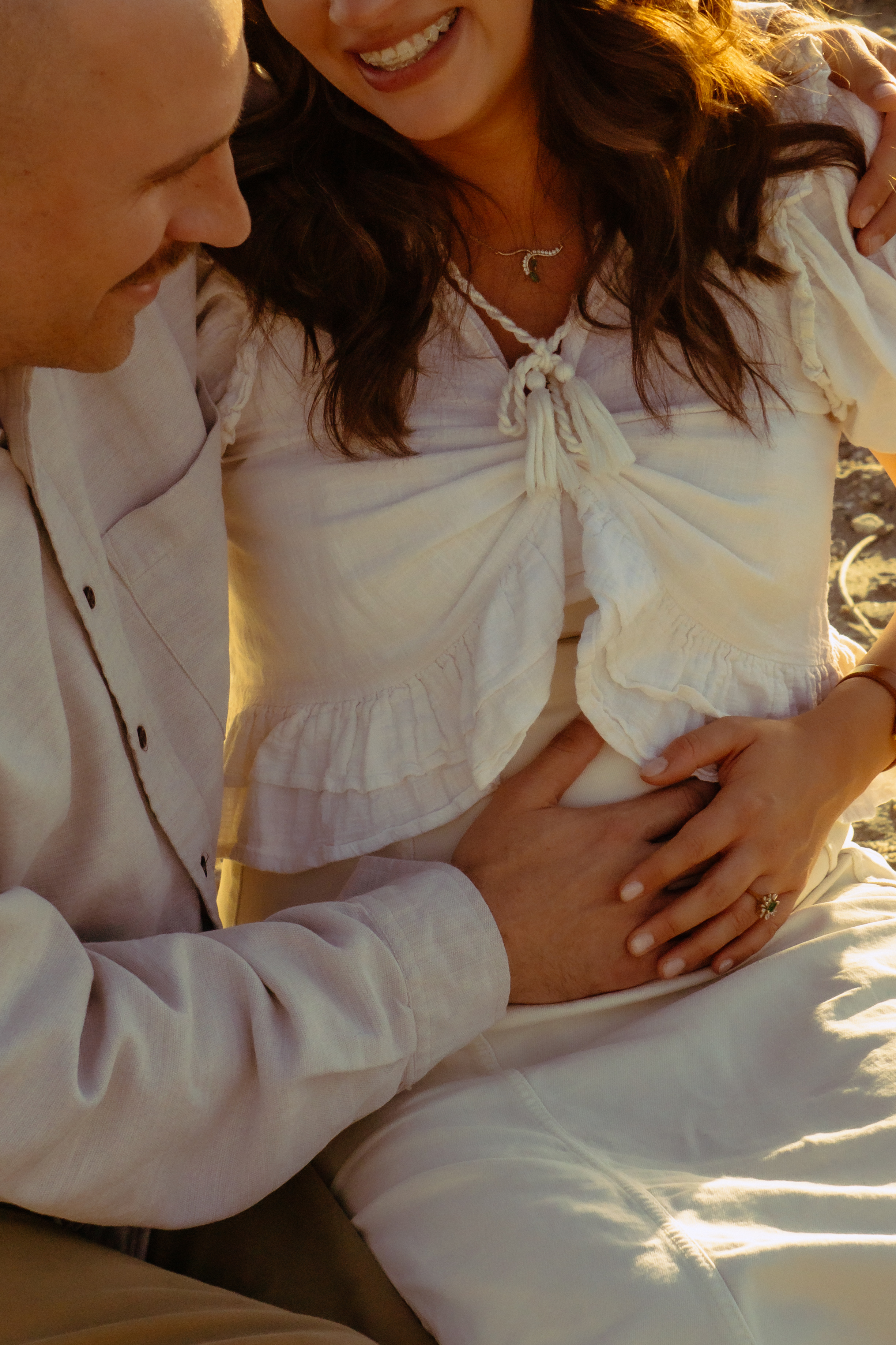 Family — Couple cradling expectant belly at the beach