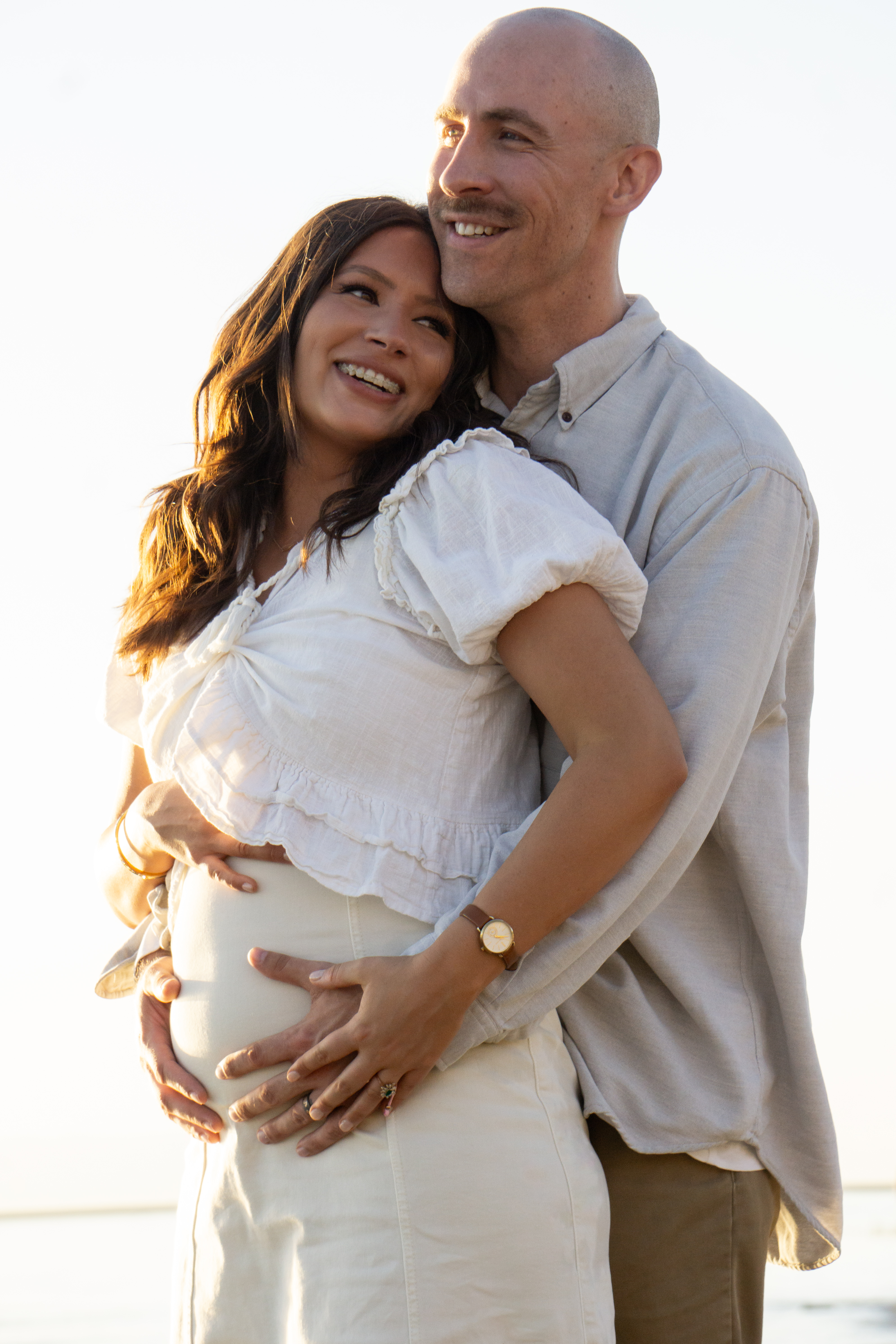 Family — Expectant couple smiling together at the beach