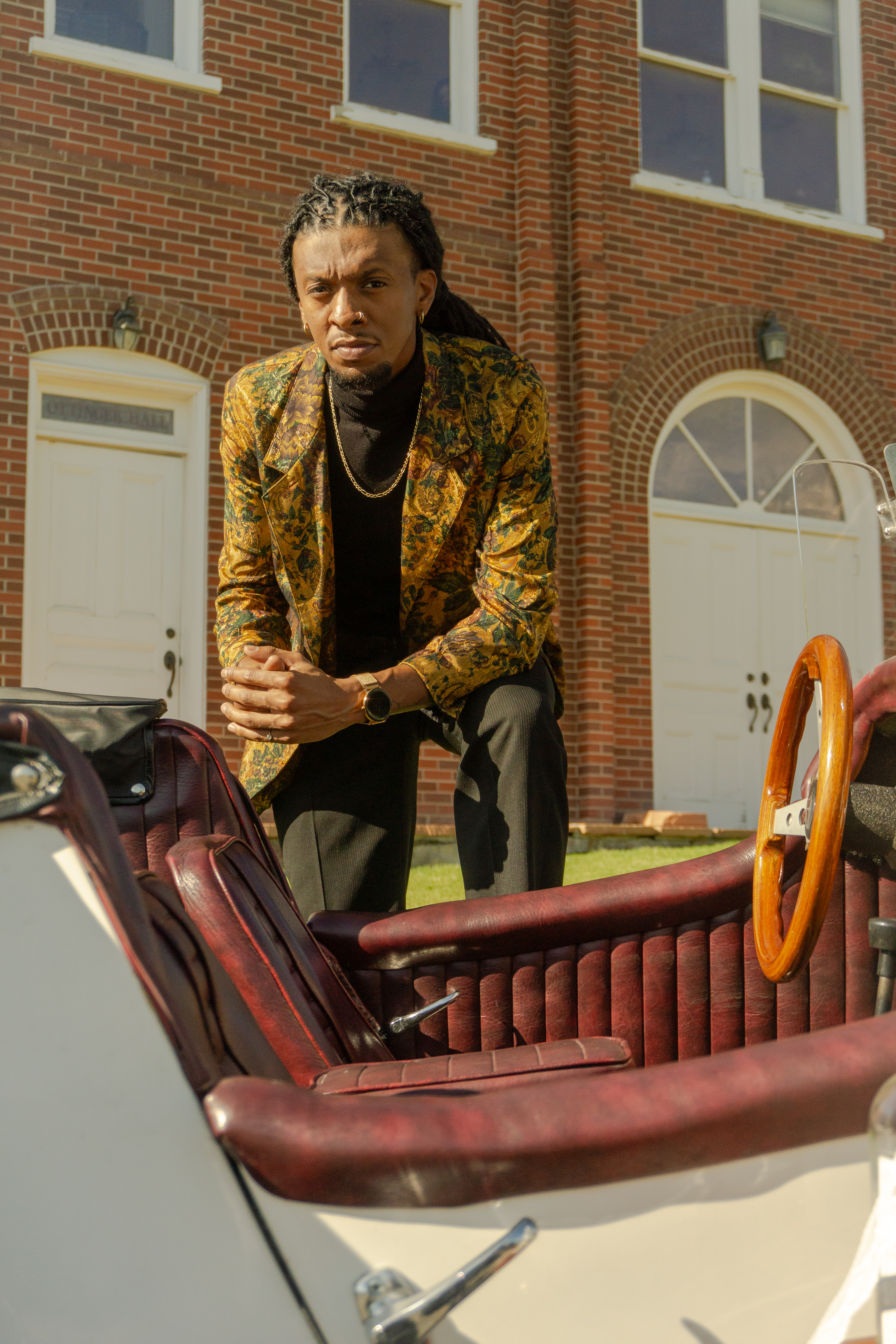 Portrait — Man in gold jacket leaning on a vintage car