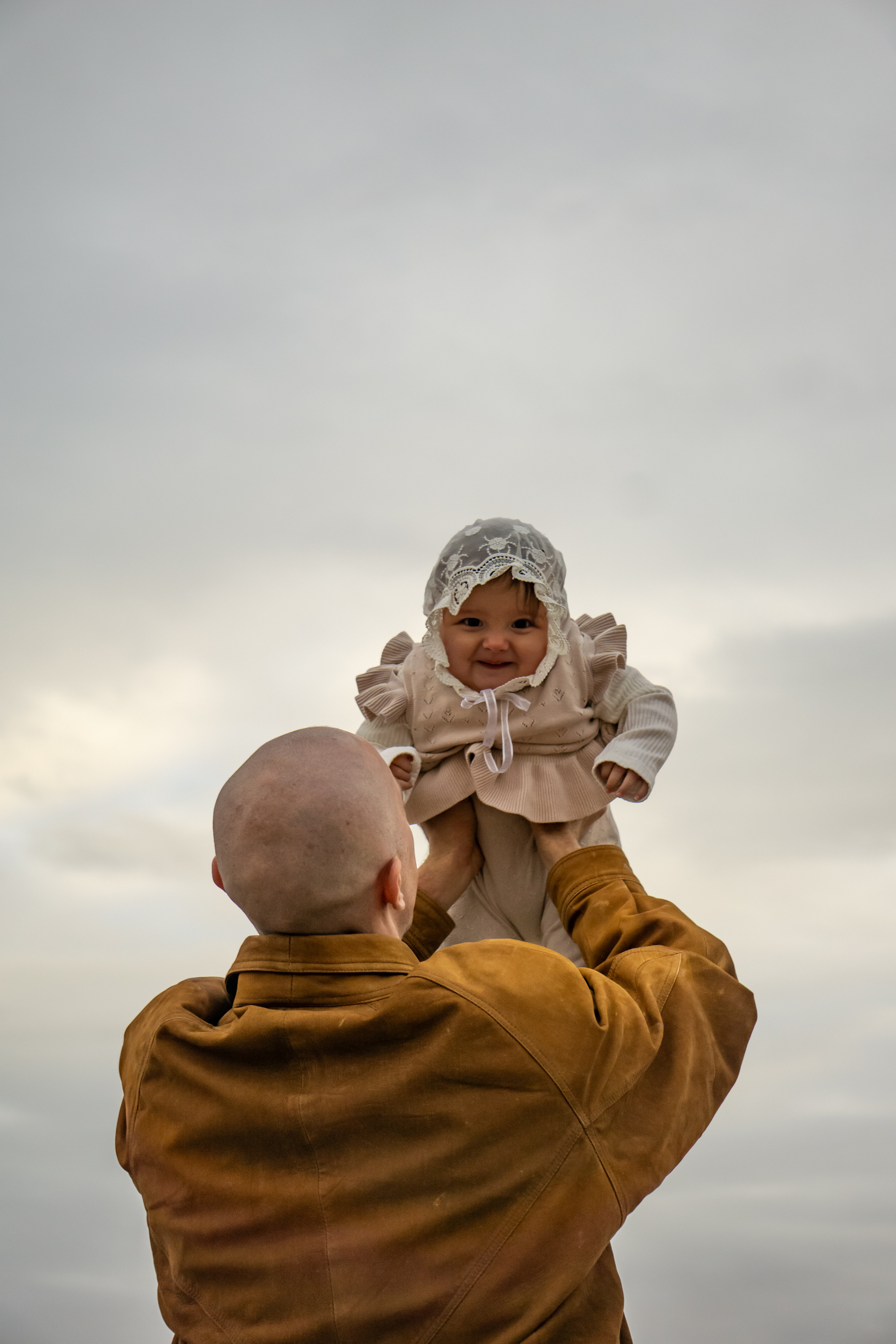 Family — Father lifting a laughing baby toward the sky