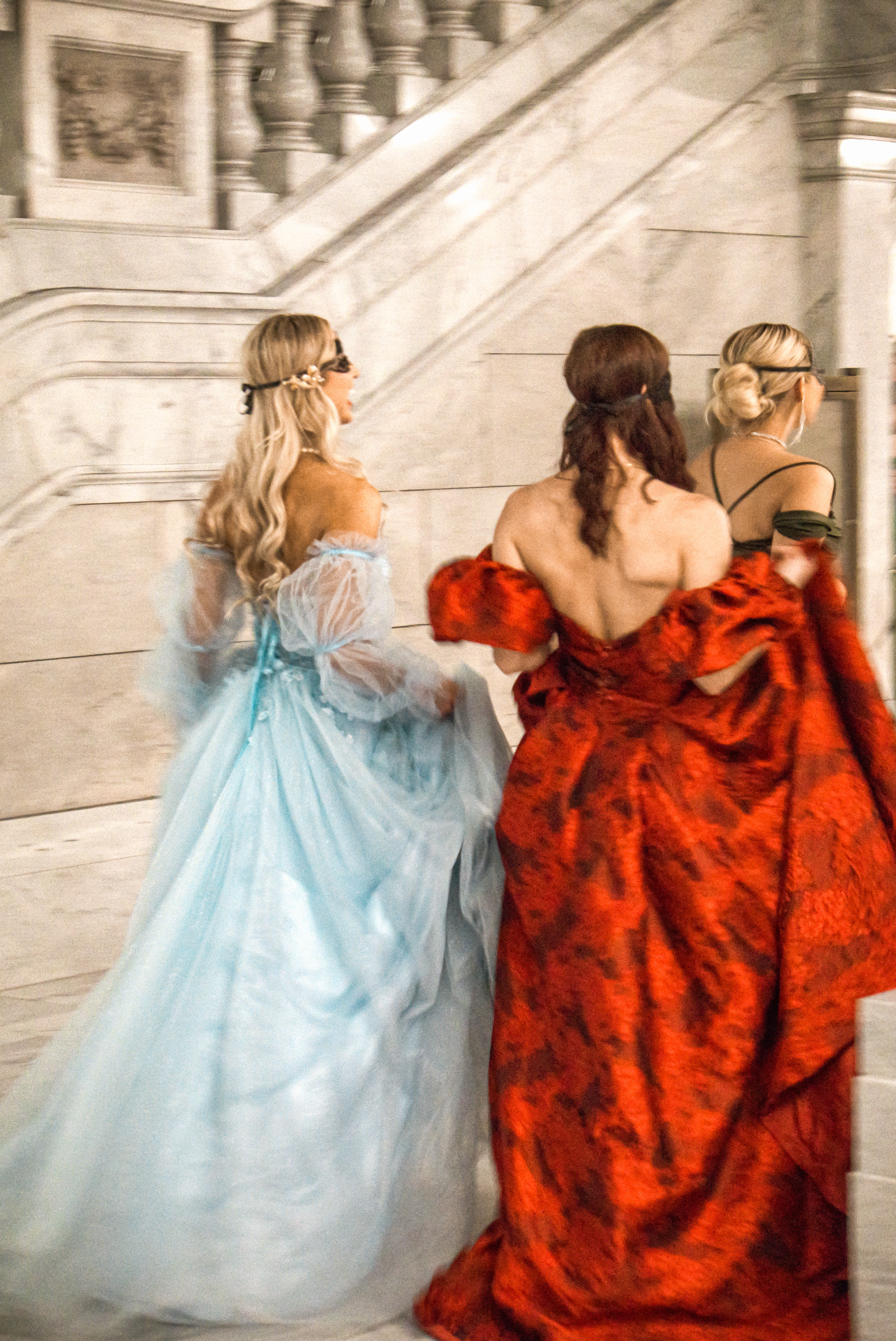 Fashion — Three women in ball gowns ascending marble stairs